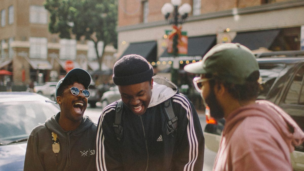 Three young men laughing together on a city street